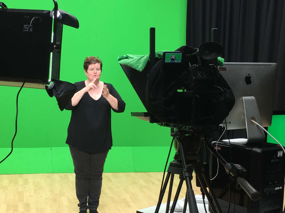 A woman standing in front of a green screen.